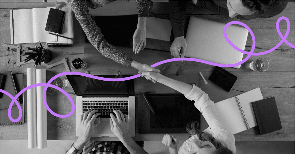 An overhead view of several people working together at laptops around a table.