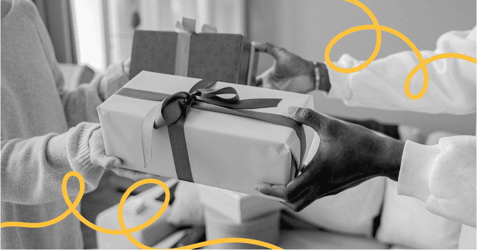 Hands holding a stack of wrapped gift boxes tied with ribbon.