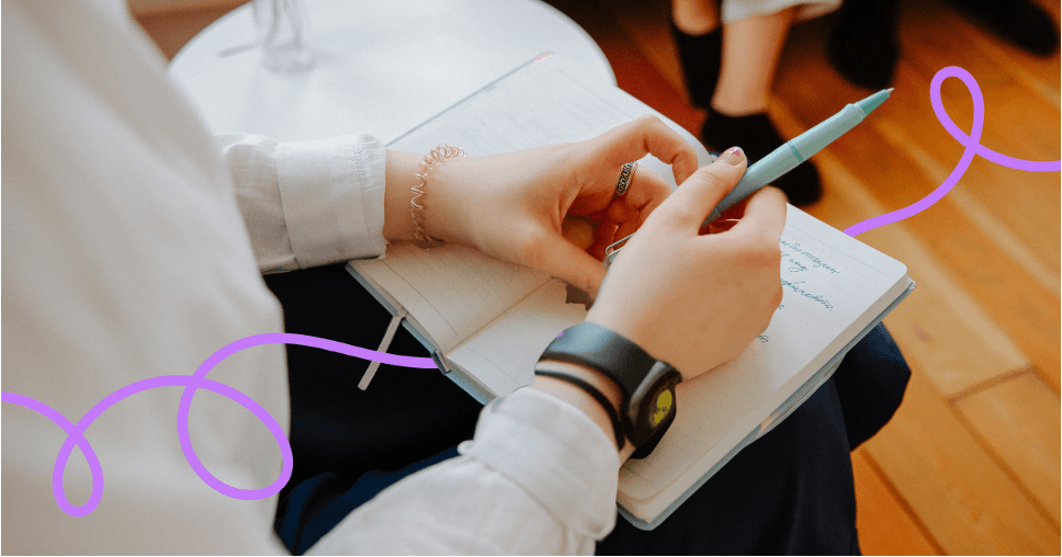 A close-up of someone writing notes in a notebook with a pen.
