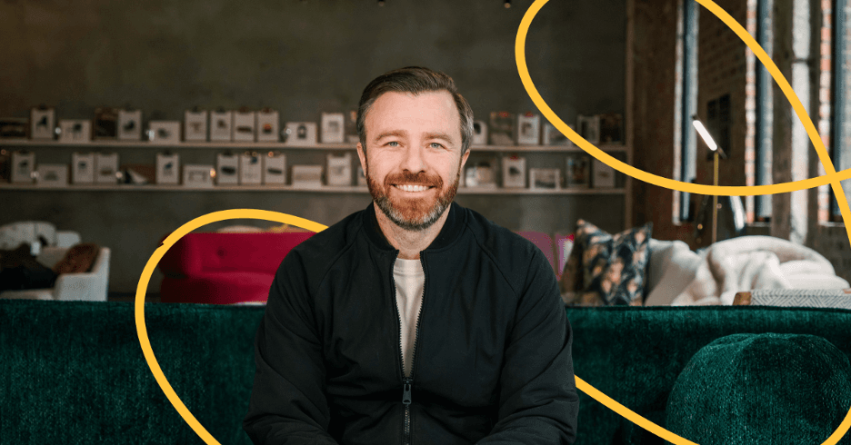 Jason Bagley sitting on a green sofa, smiling at the camera.